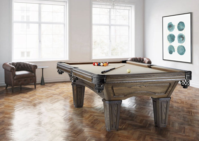 Vintage-style pool table in dark oak with tan cloth, leather drop pockets and paneled legs on a herringbone floor